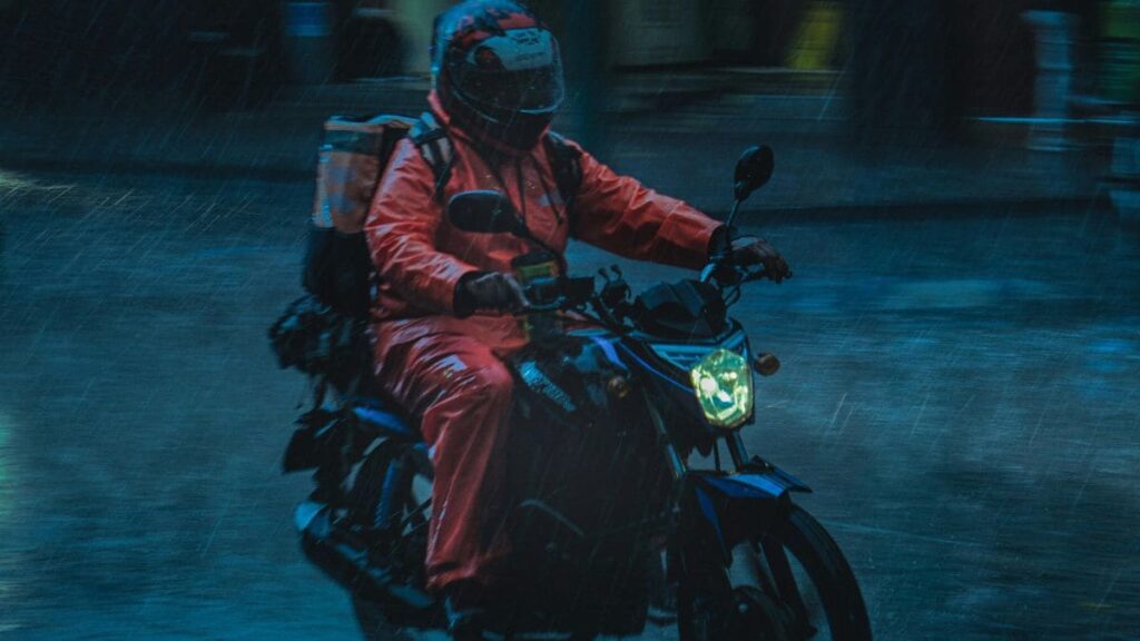 Entregador de moto usando capa de chuva