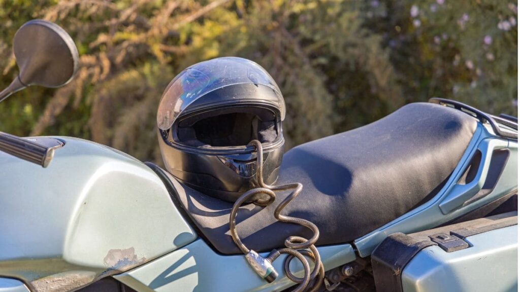 Capacete preso com corrente no banco da moto