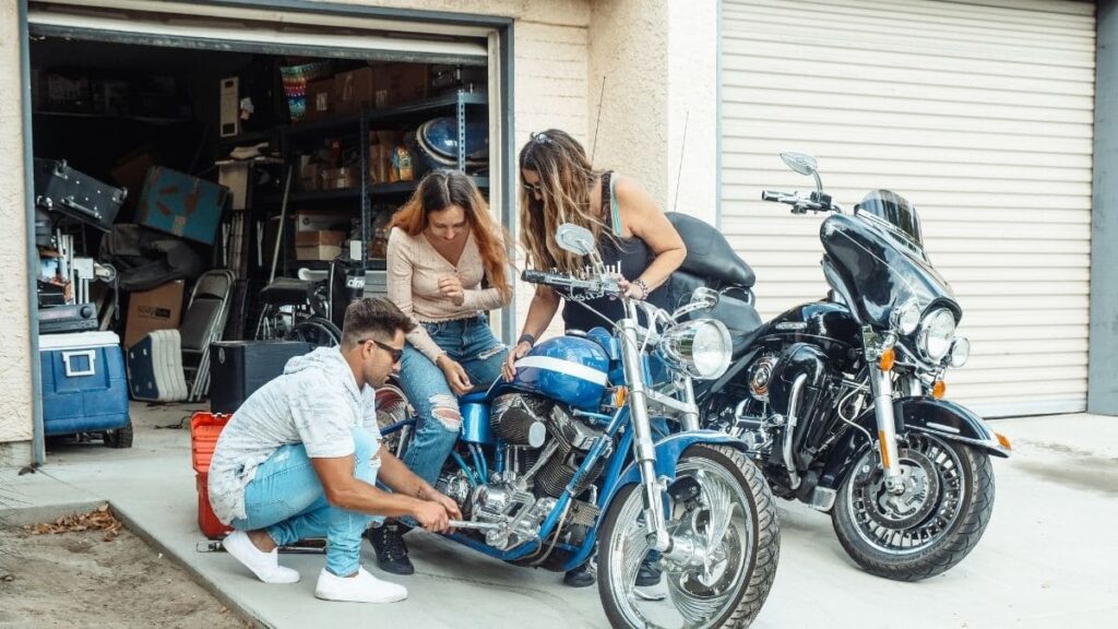 Mulher sentada na moto, e mecânico mexendo no pedal.