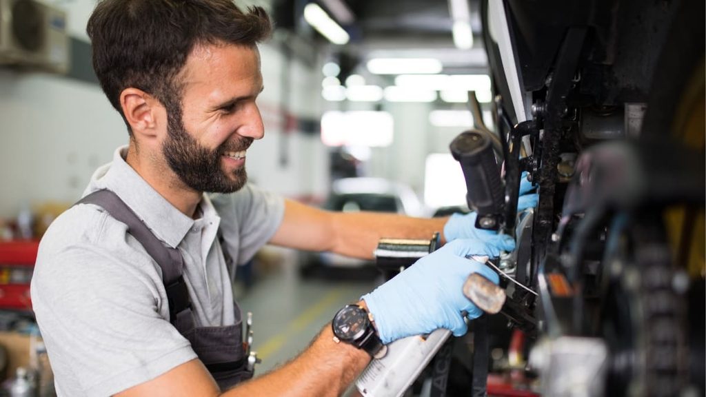 Profissional fazendo aplicação de produto na corrente da moto.